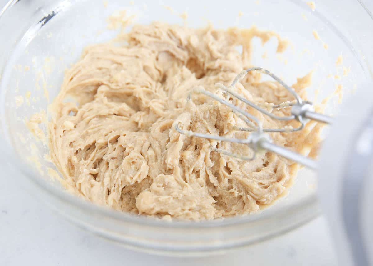 Using an electric mixer to cream butter and sugar in a bowl.