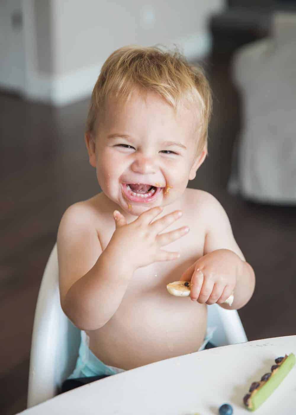 Smiling toddler eating ants on a log.