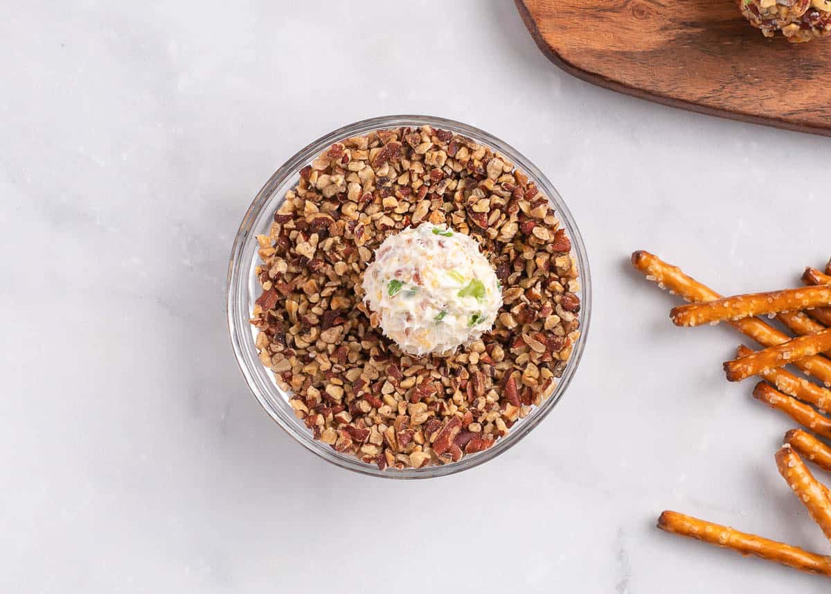 Rolling a cheese ball bite in pecans.