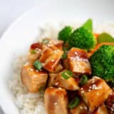 Teriyaki chicken bowl with rice and stir fry veggies in a white bowl.