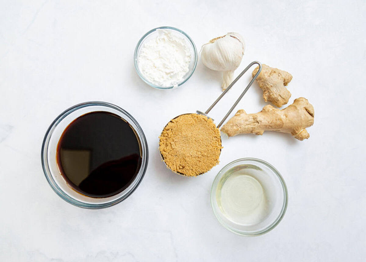 Soy sauce, cornstarch, brown sugar, garlic, rice vinegar and ginger on the countertop.