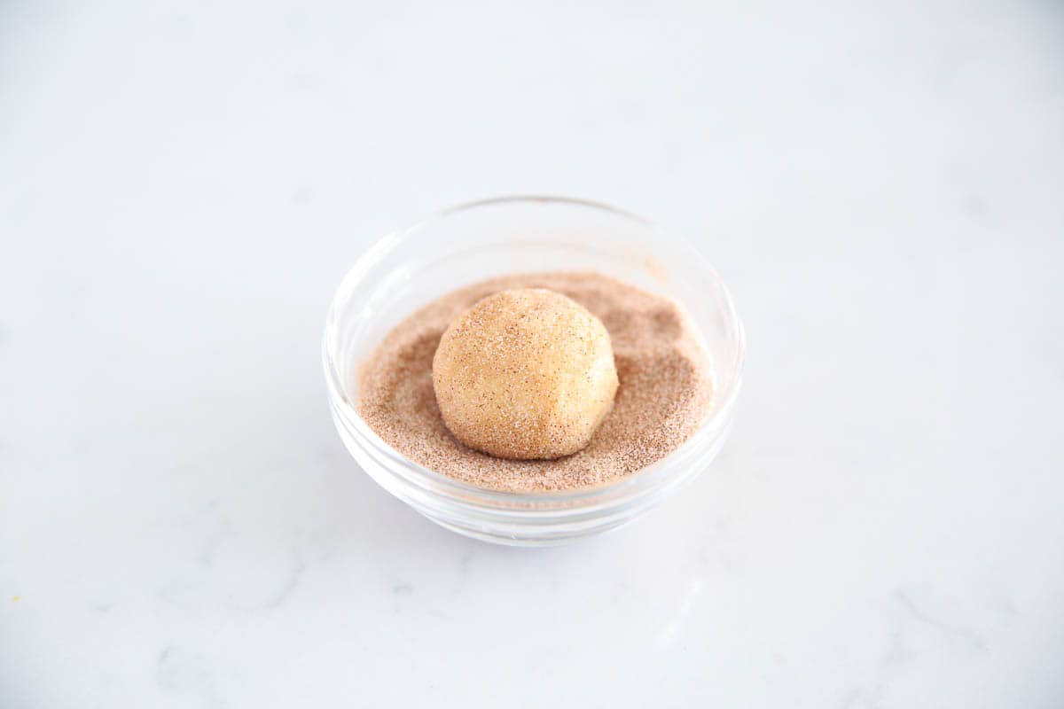 Rolling a snickerdoodle in bowl of cinnamon sugar.