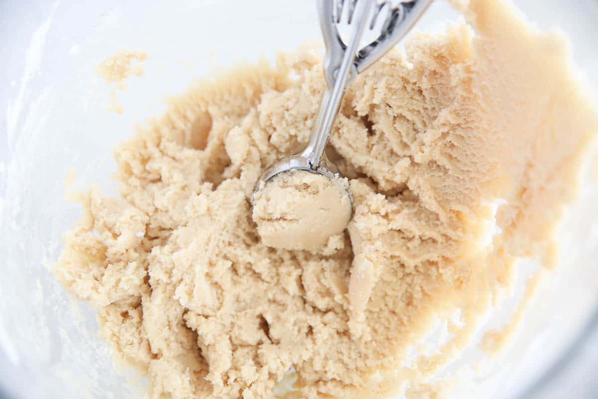 Snickerdoodle cookie dough being scoop with cookie scoop.