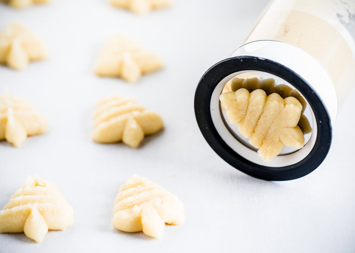 Pressing spritz cookies through a cookie press.