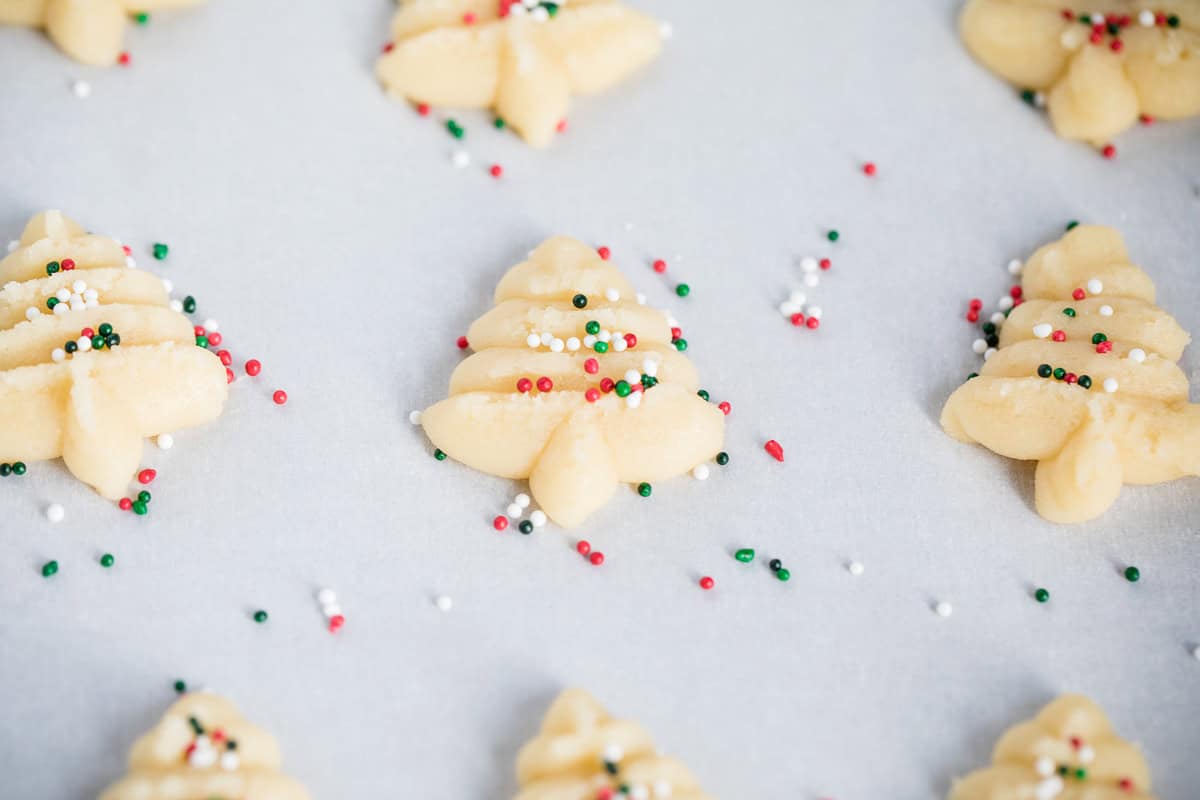 Spritz cookies shaped into Christmas trees with sprinkles.