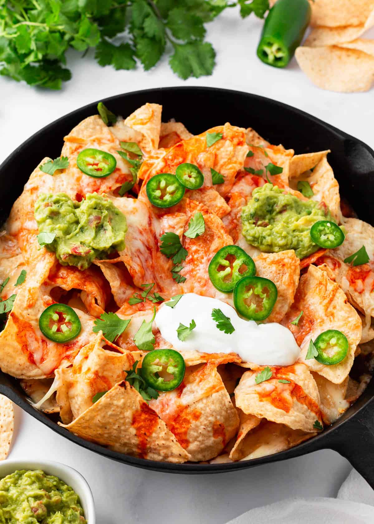 Baked nachos in a skillet loaded with toppings.