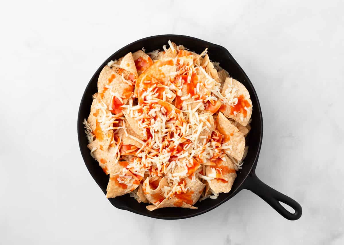 Nachos layered in a cast iron skillet ready for the oven.