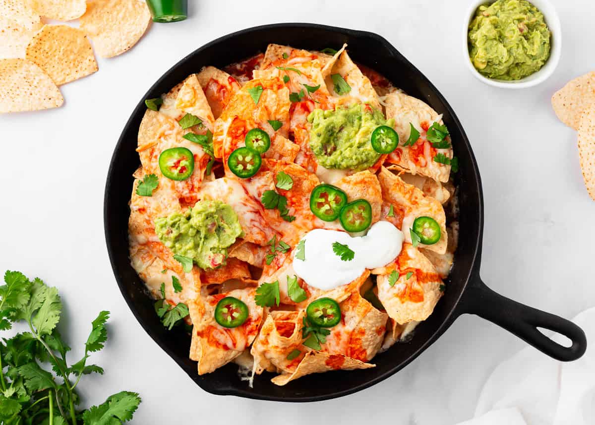 Oven baked nachos loaded with toppings on the counter.