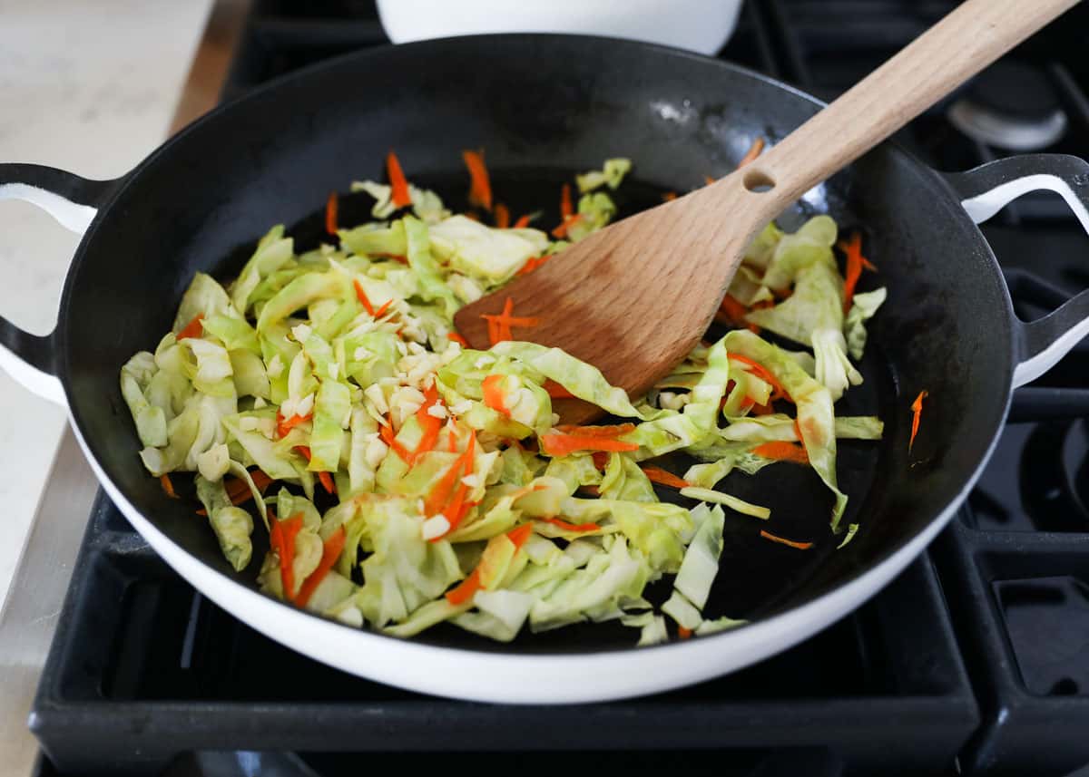 Stir frying carrots and cabbage in a skillet.