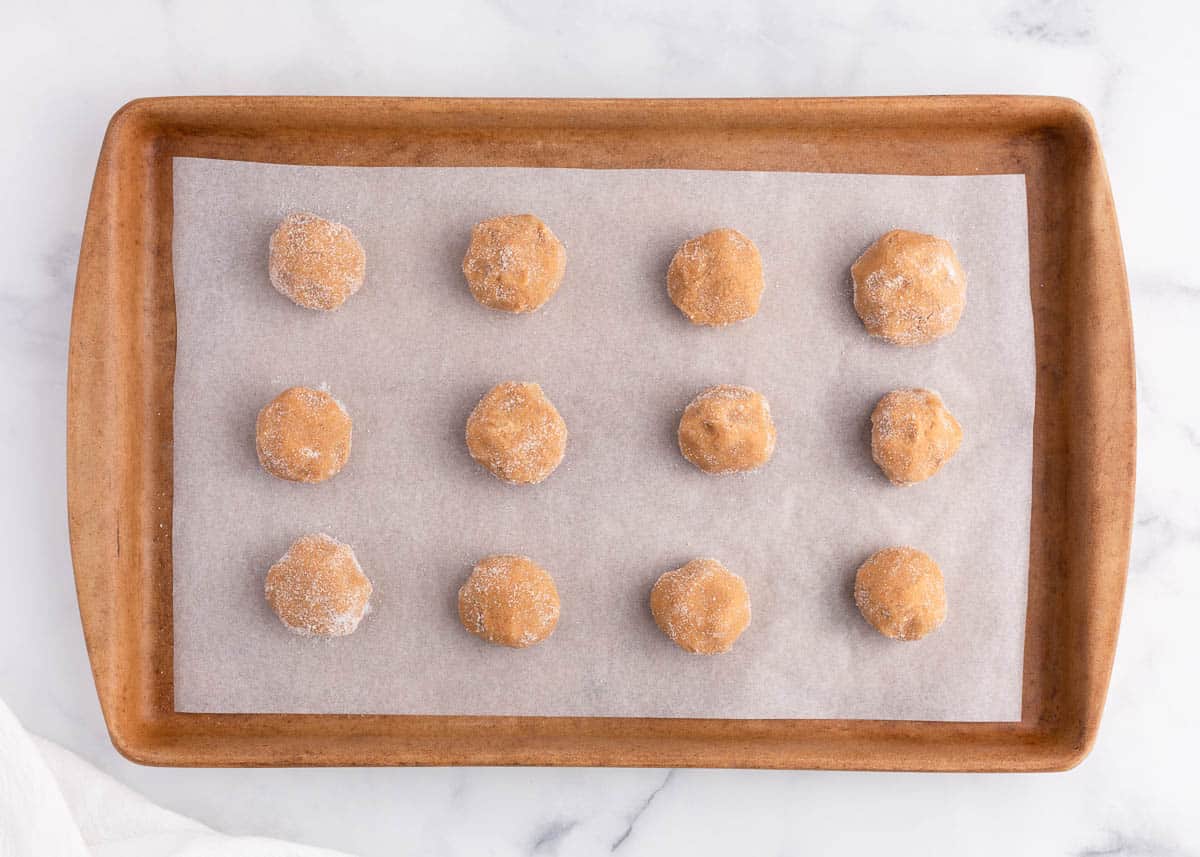 Peanut butter cookie dough balls on baking sheet.