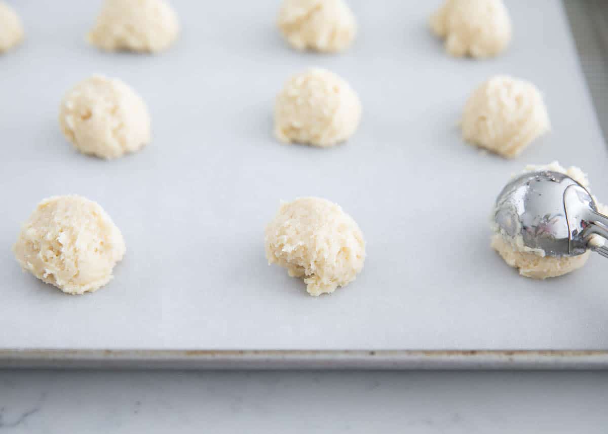 Scooping cookie dough balls on baking sheet.