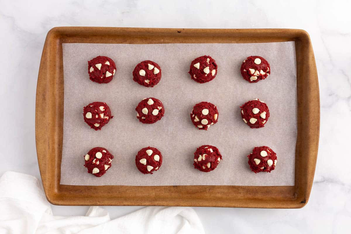 Red velvet cake mix cookies on parchment lined baked pan.