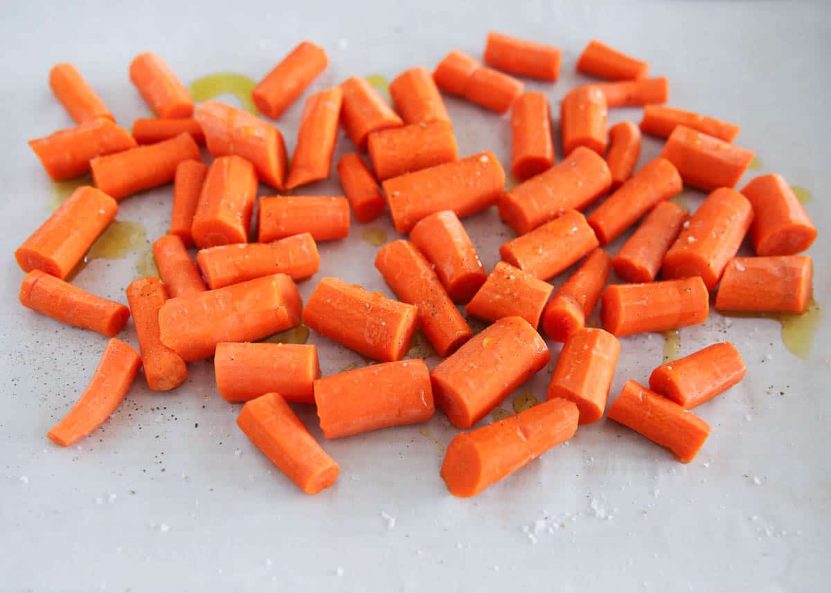 Carrots tossed with olive oil on baking sheet.