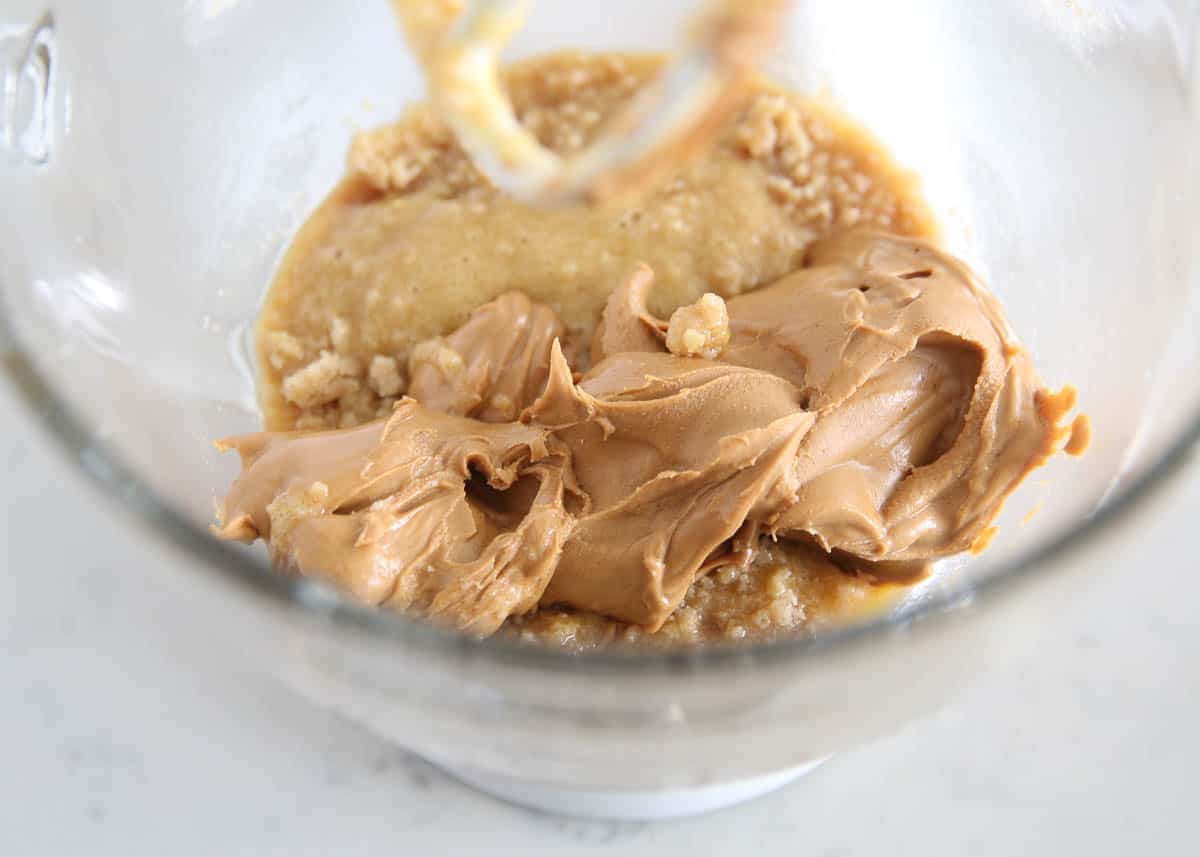 Adding peanut butter to a mixing bowl.