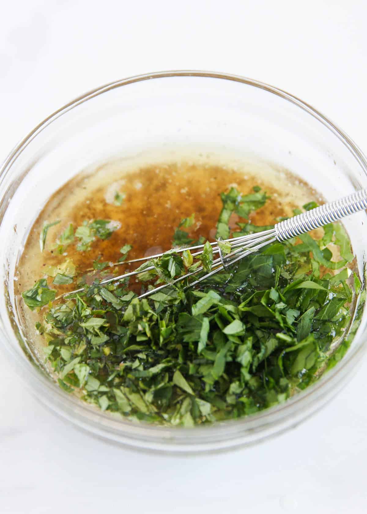 Greek chicken marinade in a bowl with whisk.