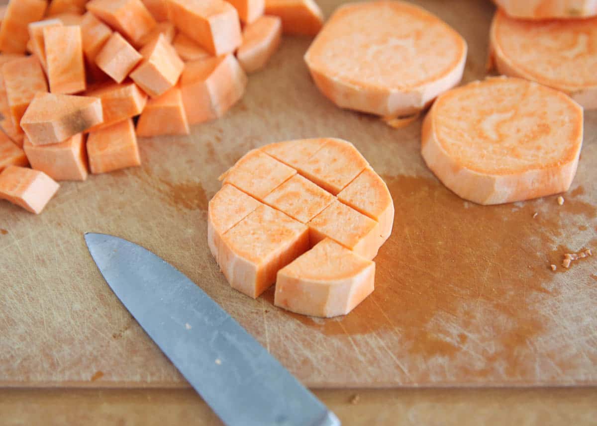 Cutting sweet potatoes on a cutting board.