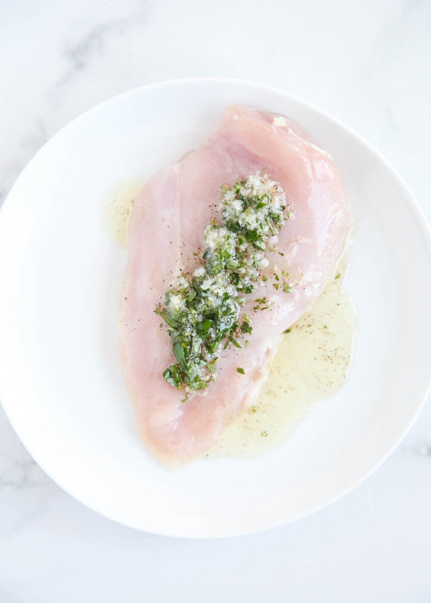 Chicken with Greek marinade on it on white plate.