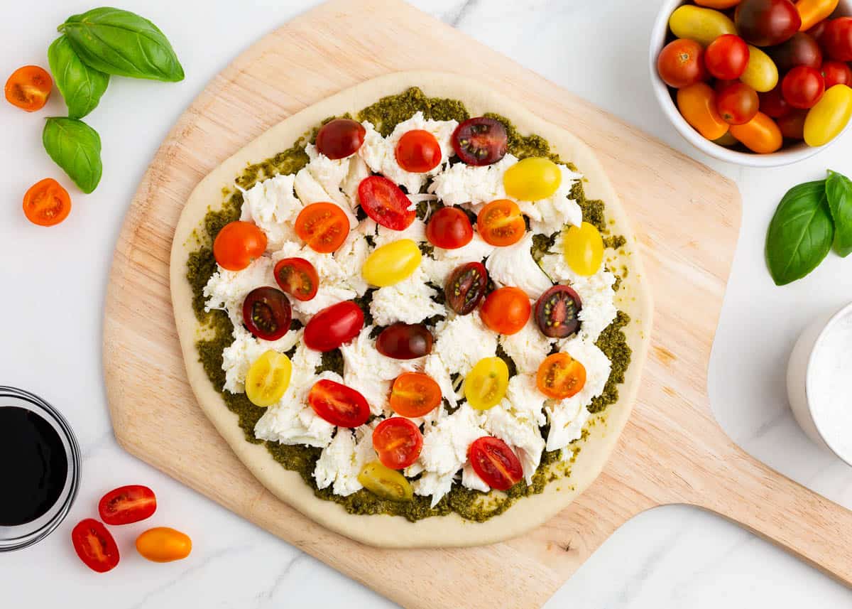 Caprese pizza on pizza peel before baking.