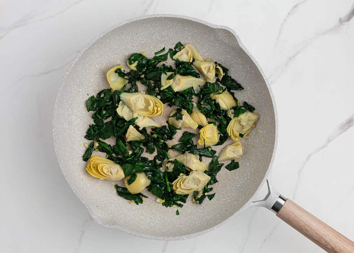 Cooking spinach and artichokes in small skillet.