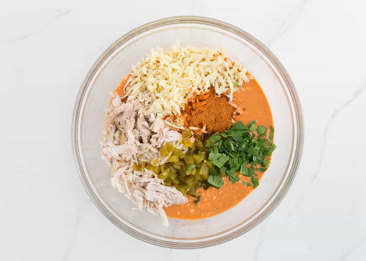 Chicken enchilada dip ingredients in a glass bowl.