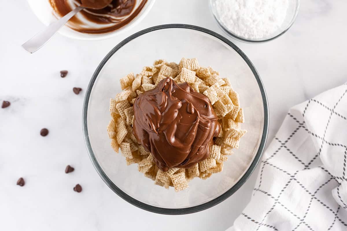 Chex cereal in a bowl with melted peanut butter chocolate mixture.