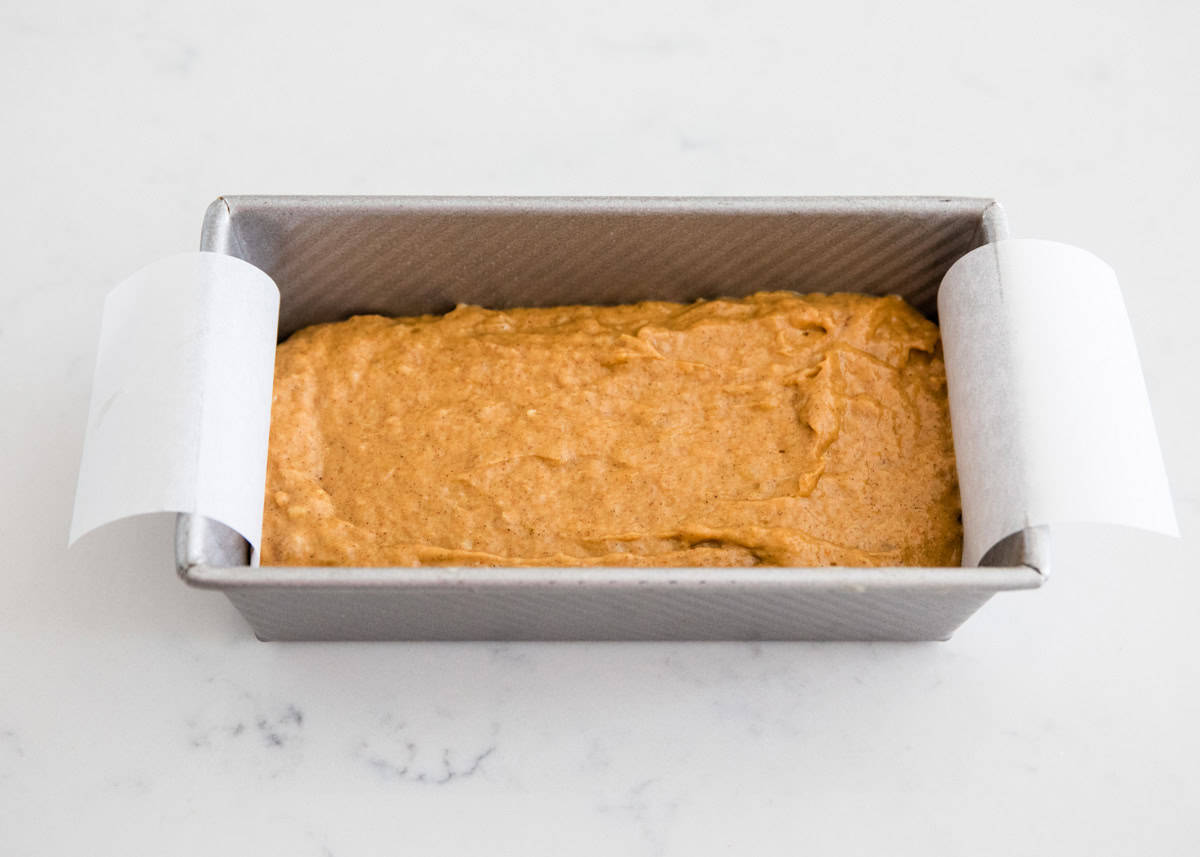 Unbaked pumpkin banana bread in a parchment paper lined loaf pan.