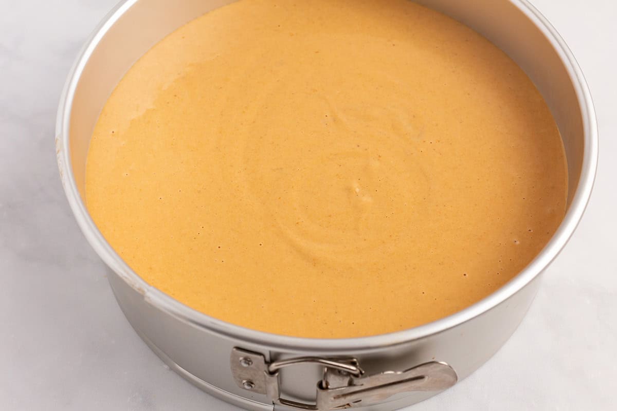 Unbaked pumpkin cheesecake in a springform pan.