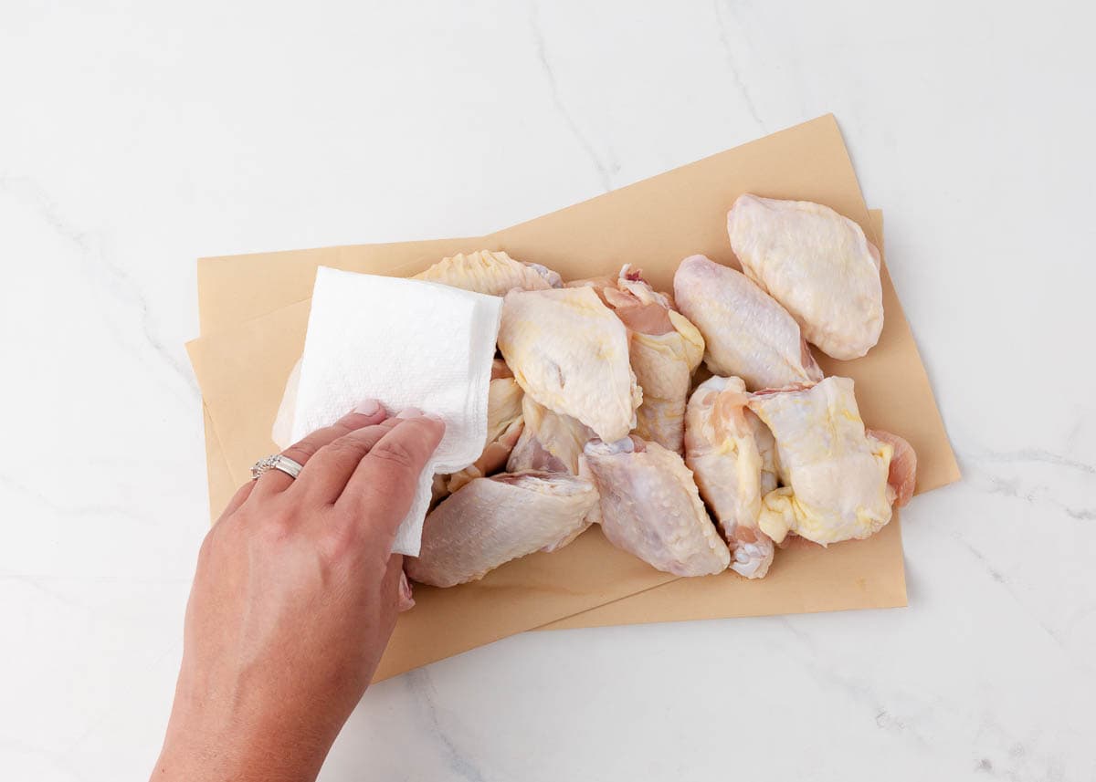 Using a paper towel to pat dry chicken wings.