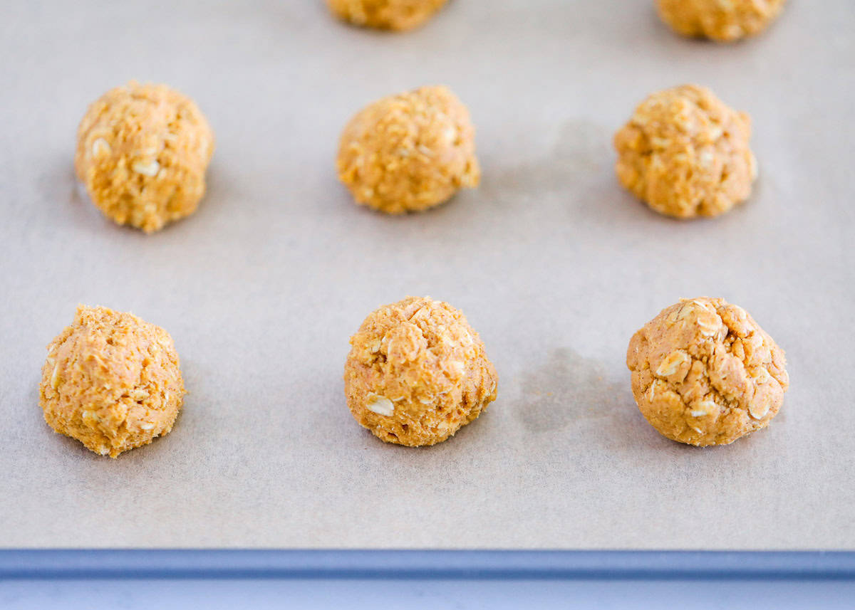 Cookie dough balls on parchment paper lined baking sheet.