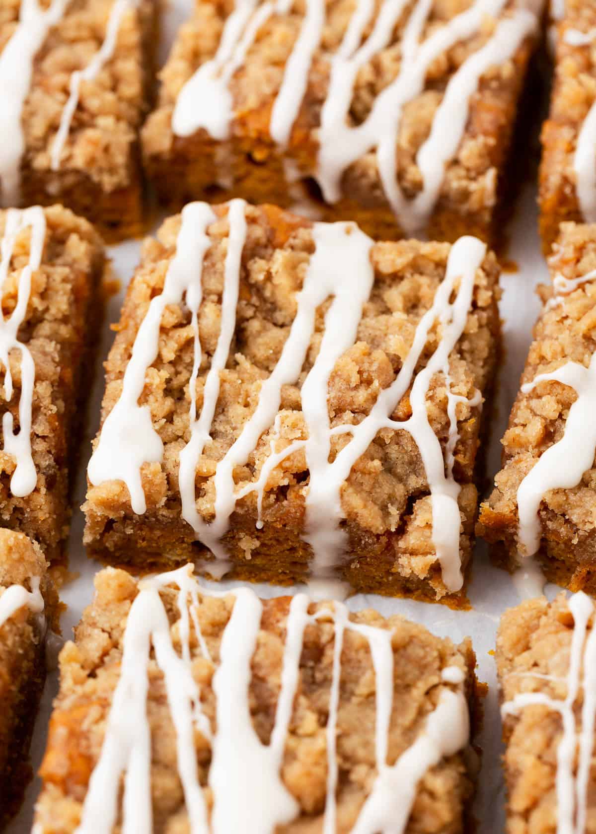 Sliced pumpkin coffee cake with streusel and glaze on top.