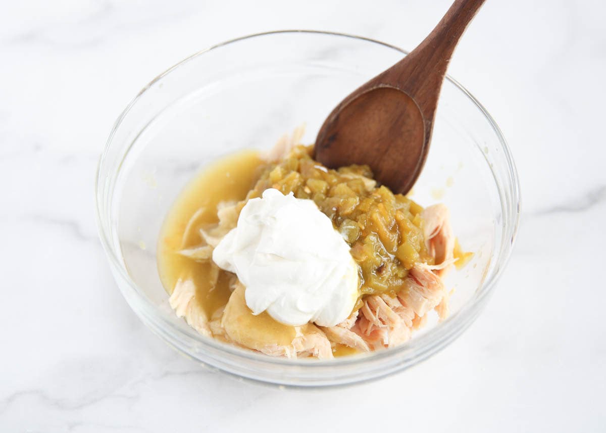 Combining chicken, green chilies and sour cream in a bowl.