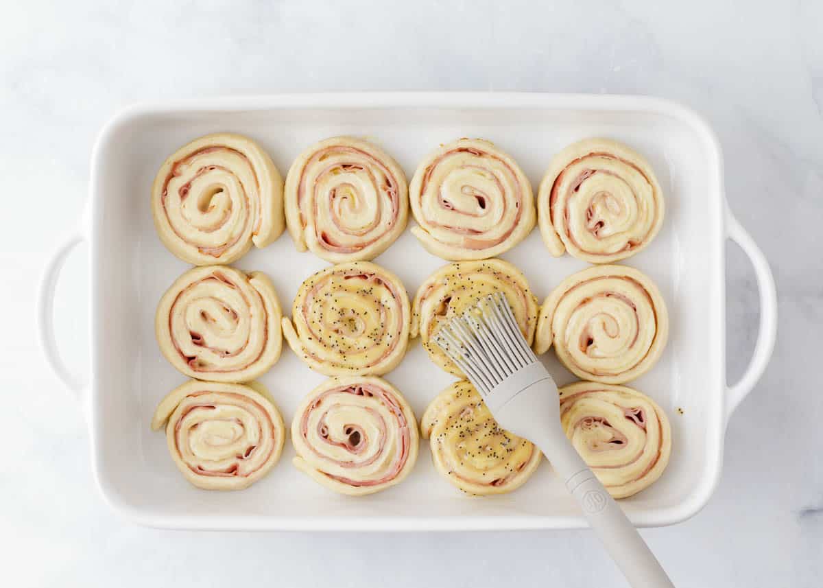 Brushing glaze on ham and cheese pinwheels.