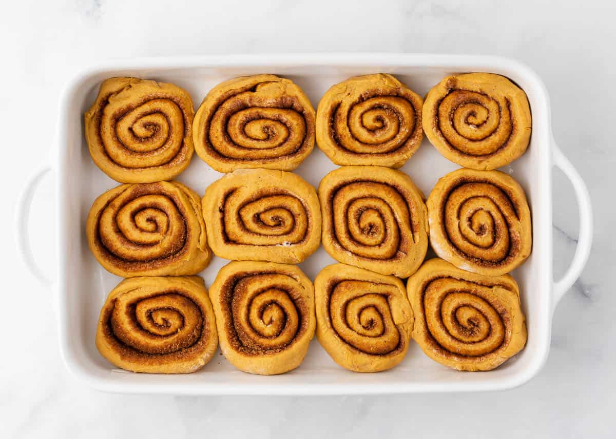 Unbaked pumpkin cinnamon rolls in a baking dish.