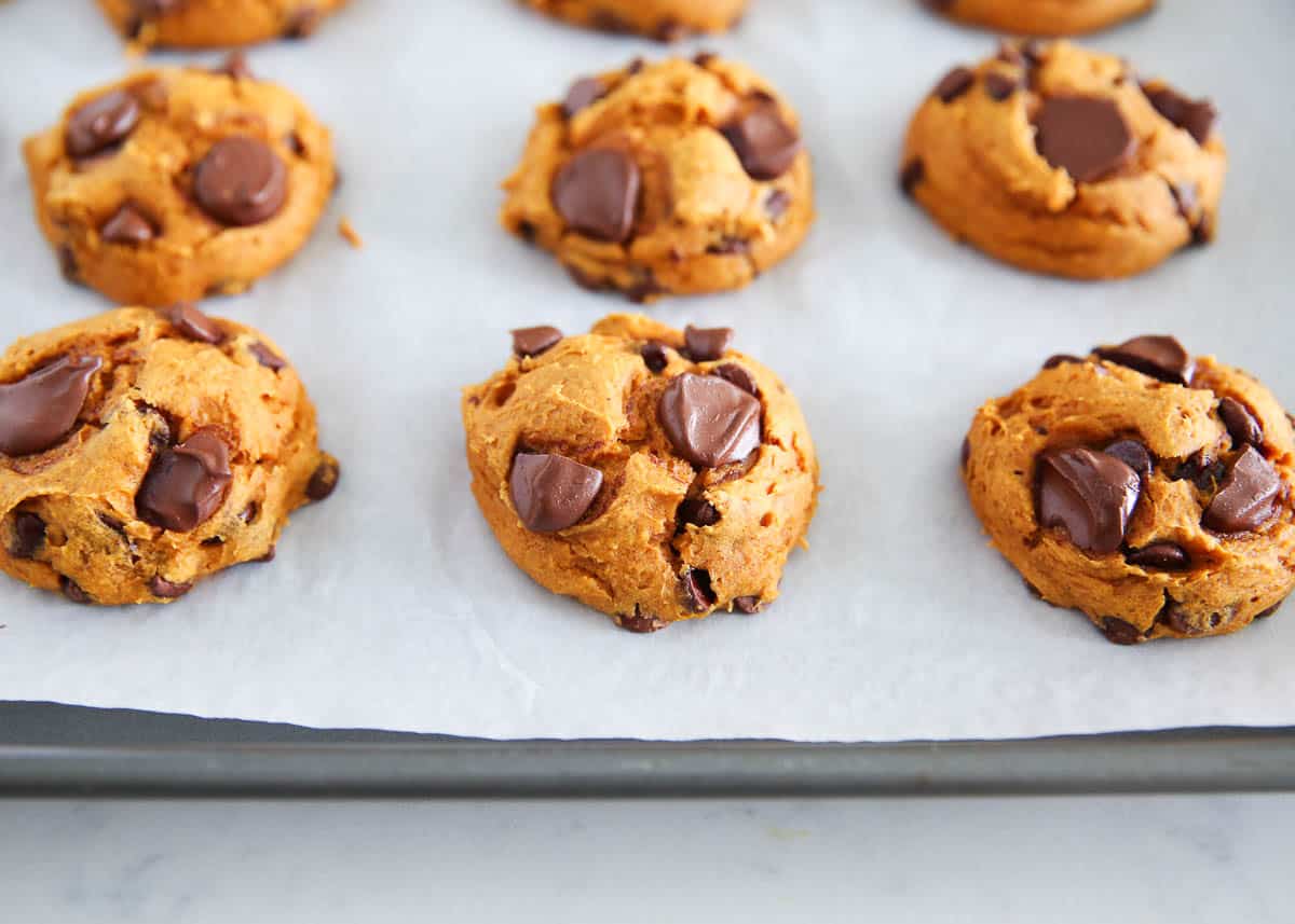 Pumpkin cake mix cookies on parchment paper lined baking sheet.