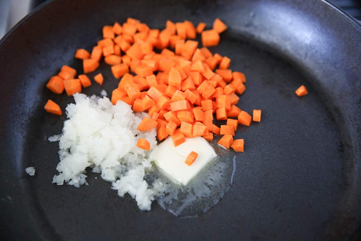 Butter with carrots and onion in a skillet.