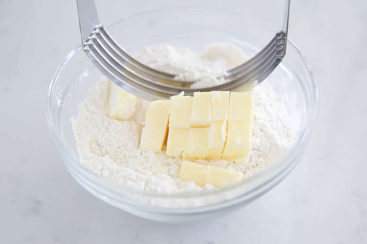 Using pastry cutter to mix in cubes of butter with flour.