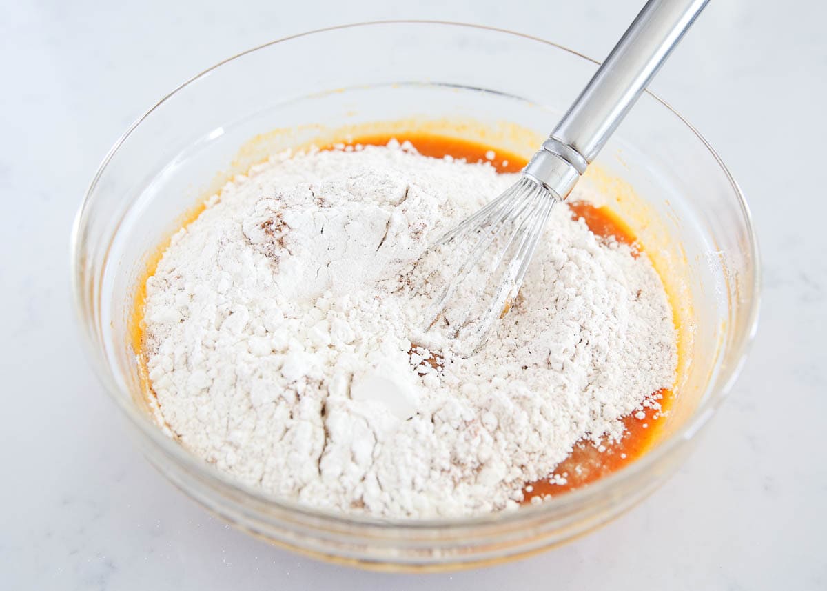 Pumpkin puree with flour mixture being stirred into it in a bowl.