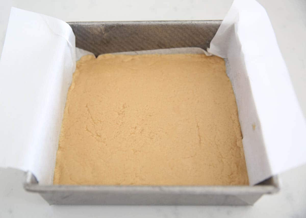 Peanut butter fudge mixture in a parchment lined baking pan.