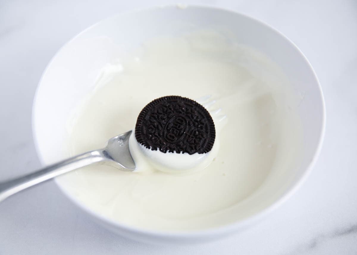 Dipping an Oreo in white chocolate.