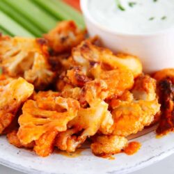 Buffalo cauliflower on a plate with vegetables and a dip.