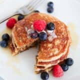 Cut oatmeal blender pancakes on a white plate with berries.