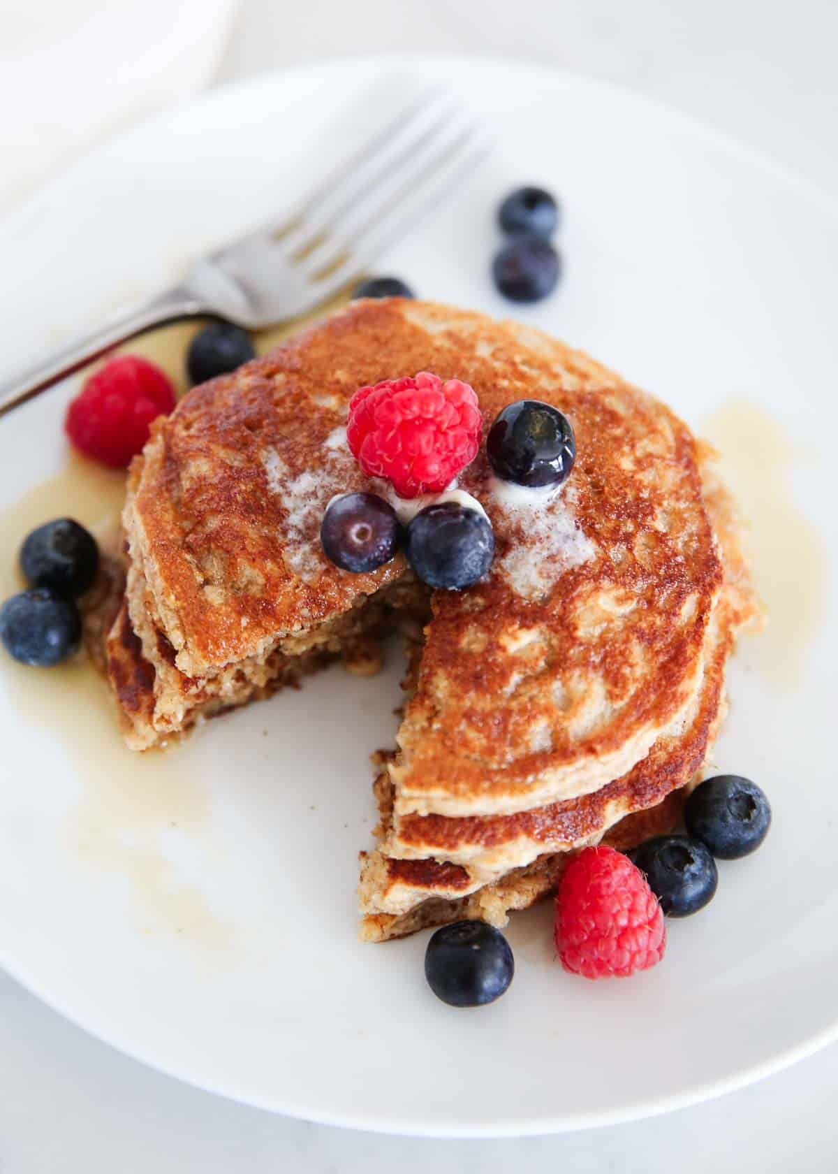 Cut oatmeal blender pancakes on a white plate with berries.