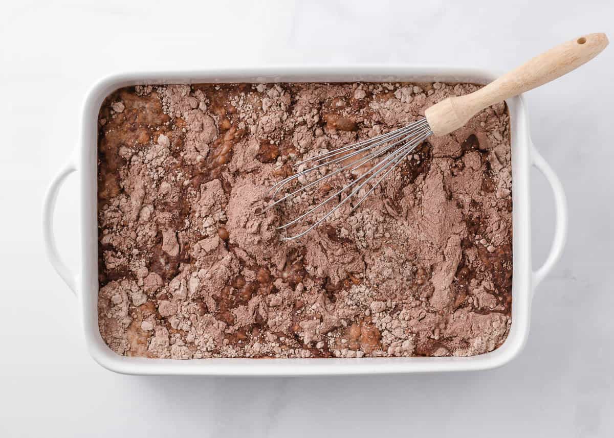 Whisking butter and milk into the dry pudding and chocolate cake mix in a baking dish.