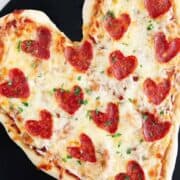 Heart shaped pizza on baking stone.