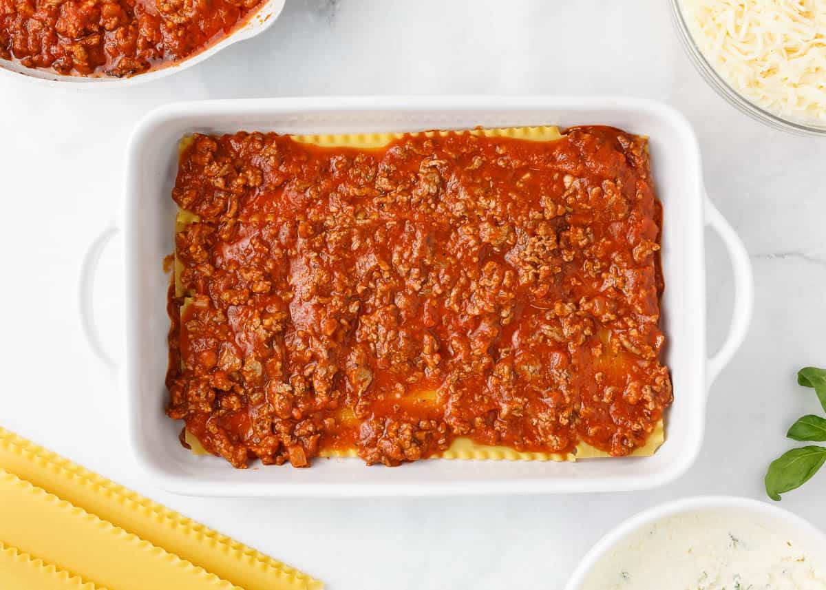 Meat sauce over a layer of noodles in baking dish.