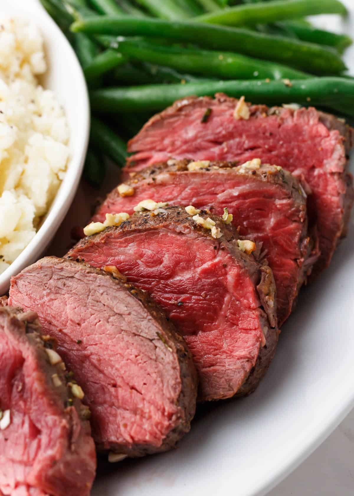 Sliced beef tenderloin on a white plate.