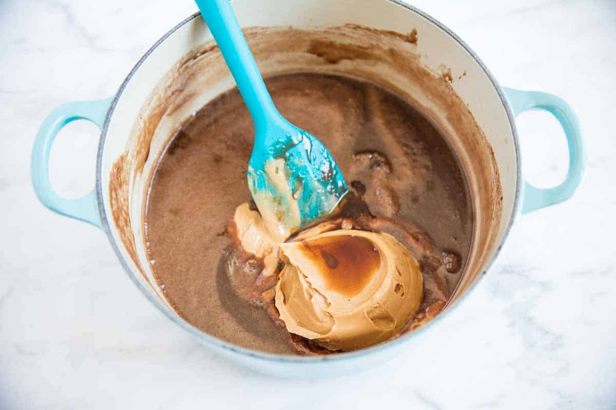 Adding peanut butter to a chocolate mixture in a pot.