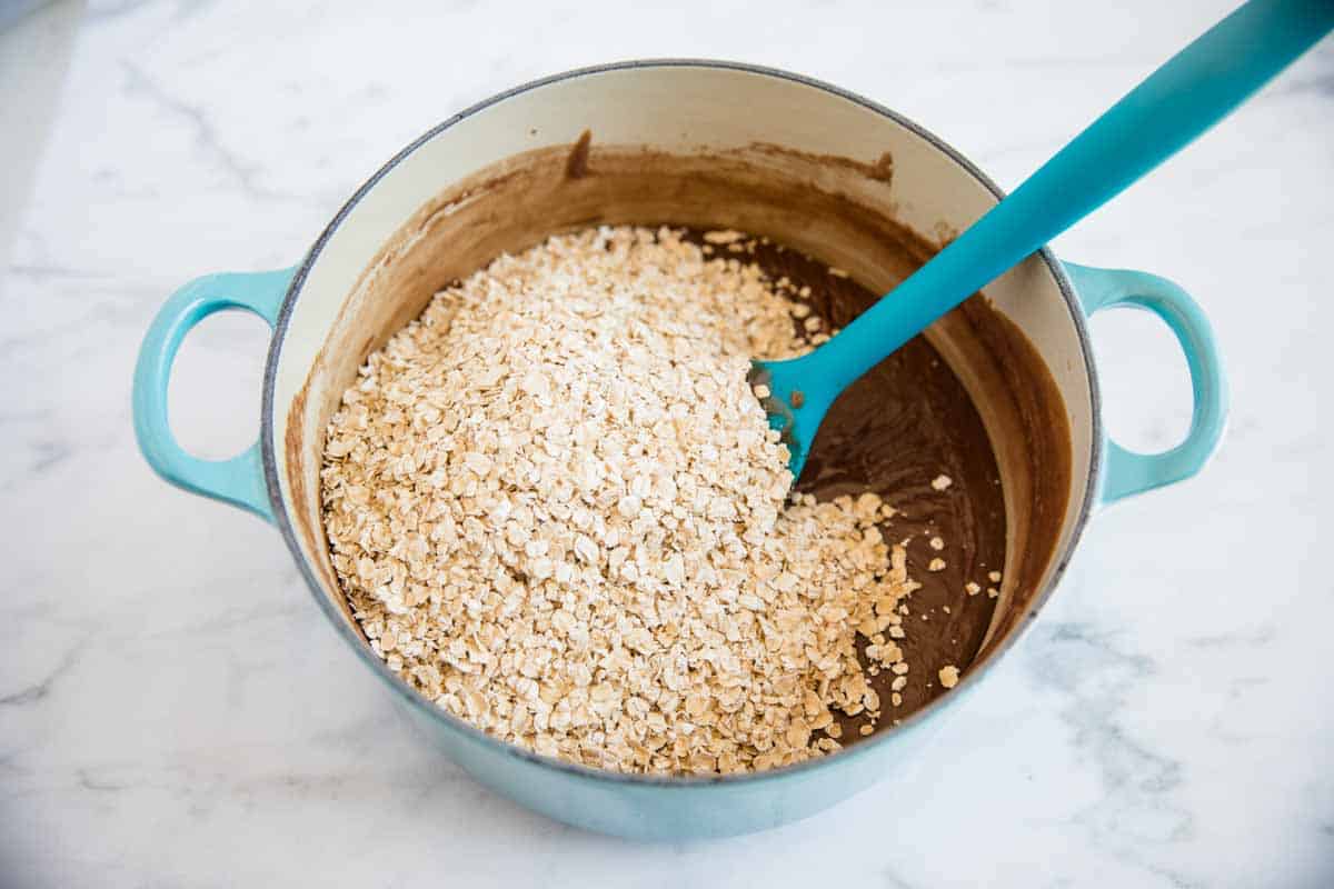 Adding quick oats to a peanut butter and chocolate mixture.