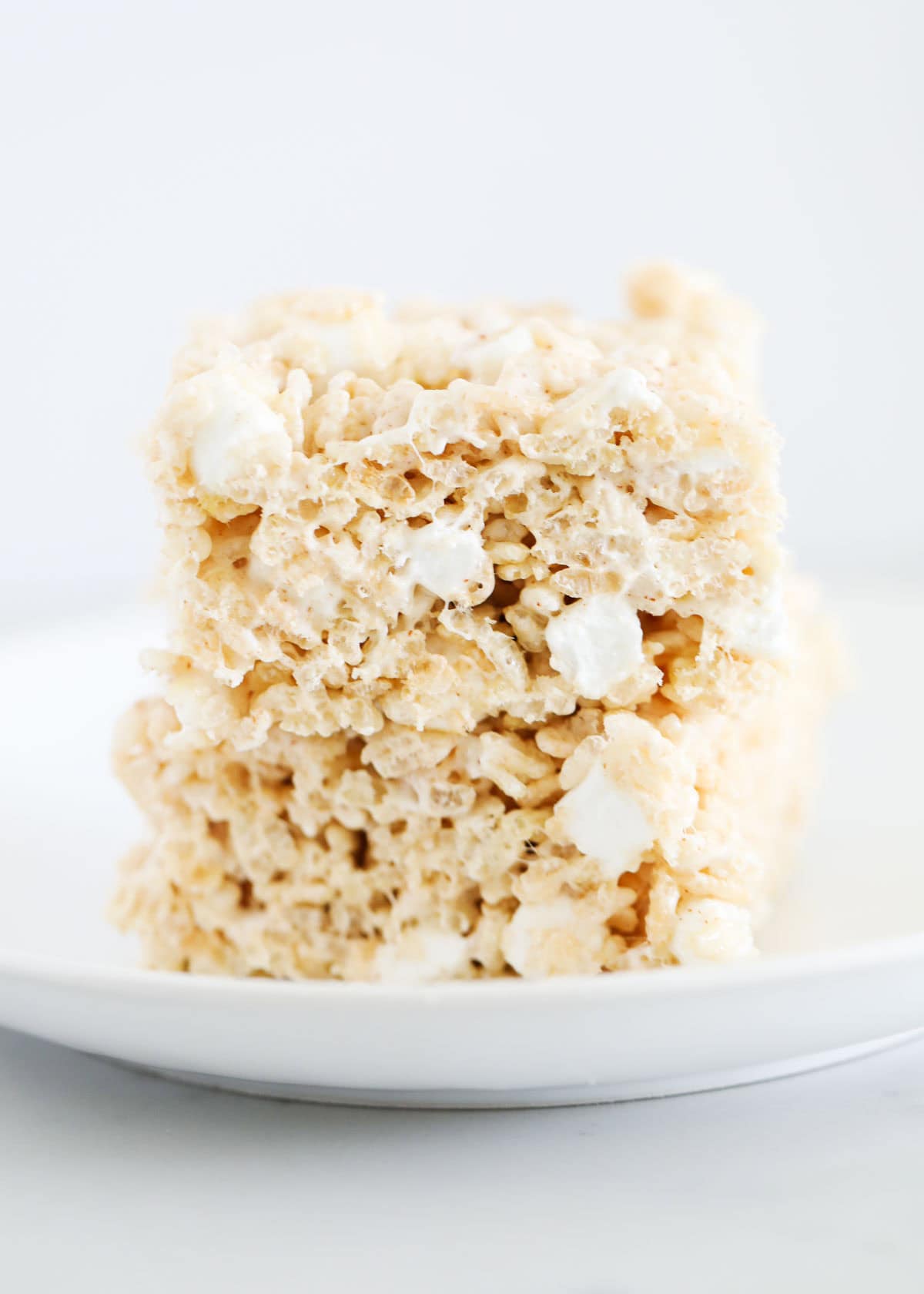 A stack of brown butter rice krispie treats on a white plate.