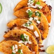 Birria tacos with onion and cilantro garnish